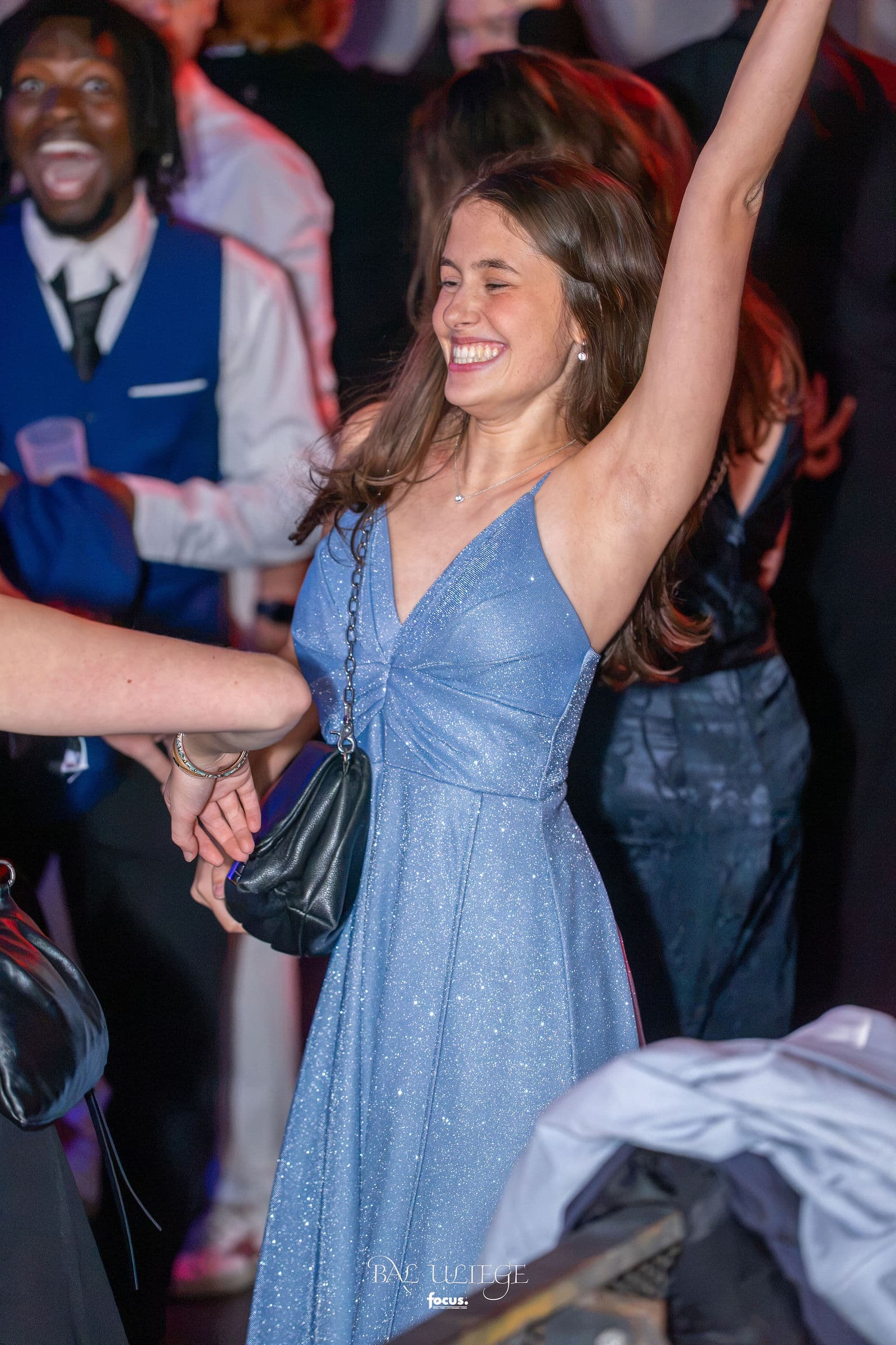 Une invitée en robe pailletée lève le bras